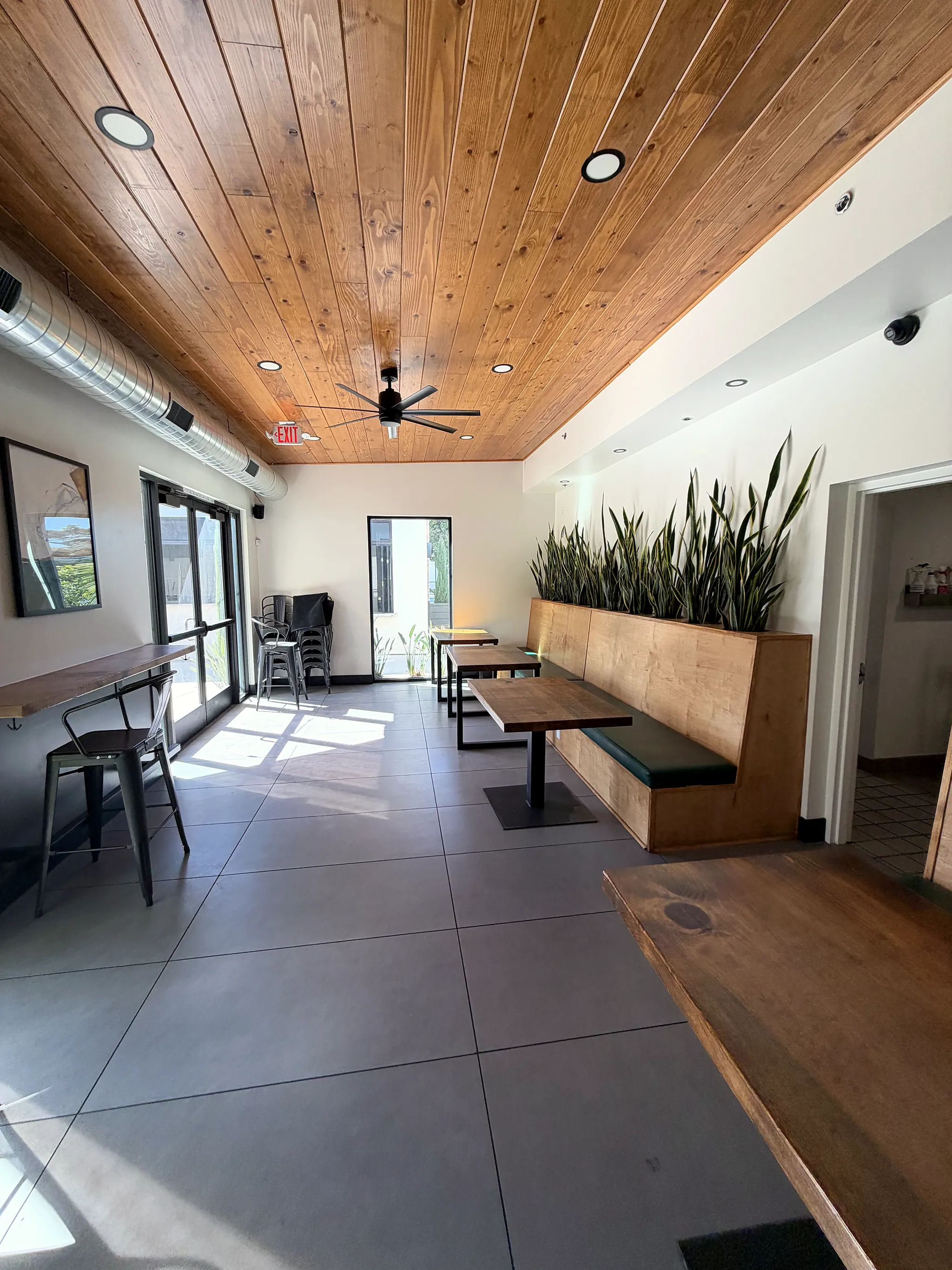 Lounge with a wood ceiling, planter banquette and two-top tables