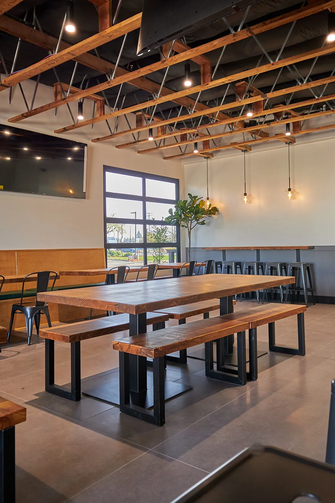 Dining room with solid wood communal tables under exposed trusses