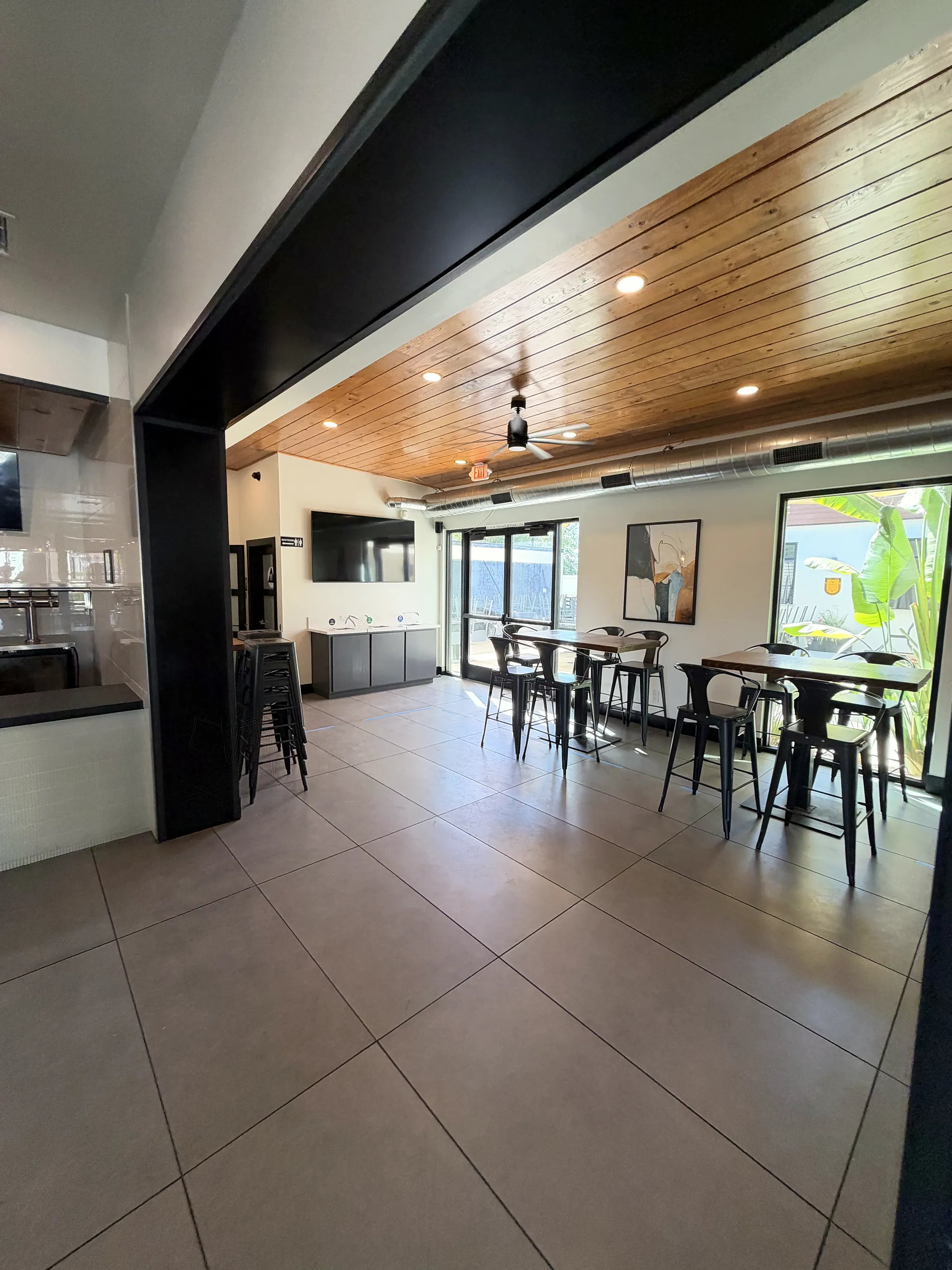 Side dining room with high-top tables and a wood plank ceiling